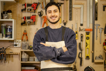 portrait of young caucasian positive carpenter at work place, handsome guy in work clothes smile...