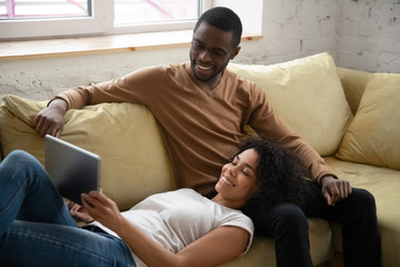 Young happy african american couple watching at tablet screen. Attractive millennial family of...