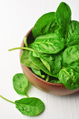 Spinach leaves in wooden bowl on white background. Healthy vegan food trend. Vegan lifestyle concept.