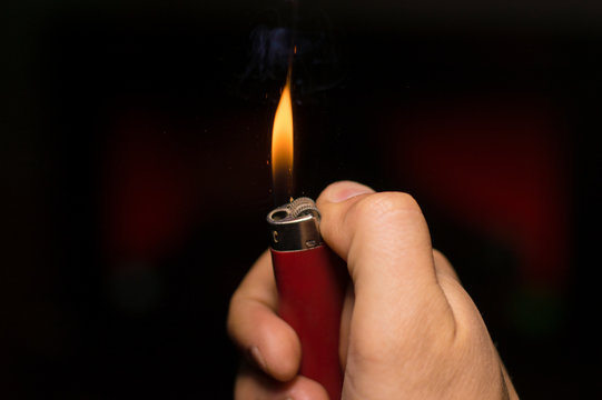 in hand a lit lighter on a dark background