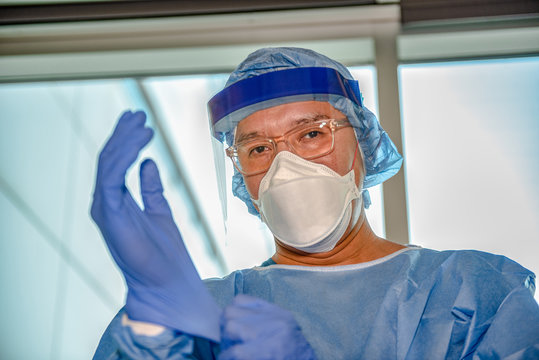 A health care professional putting on full Covid 19 (corona virus) Personal Protective Equipment. 