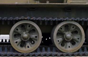 Fototapeta na wymiar Military background lateral part of heavy armored vehicles. Heavier armament tracked armored vehicles close-up. At the bottom are powerful wheels and tracks, on top are elements of external equipment.