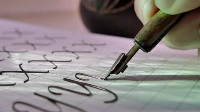 Calligraphy. Writing letter Y with fountain pen and black ink on white paper. Cinematic close-up. Slow motion.