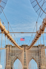 Obraz premium The United States flag on center of Brooklyn Bridge in New York, Vertically oriented shot