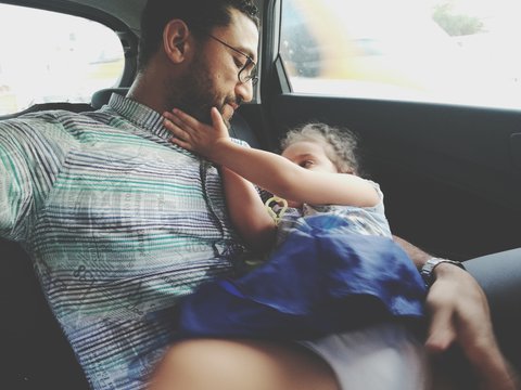 Close-up Of Girl Lying Down On Father Thigh In Car