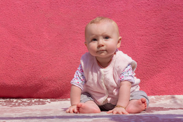Little adorable blonde baby girl sit on carpet and this cute baby looking somewhere, outside activity