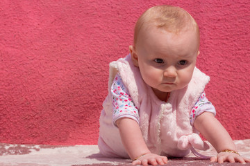 Little adorable blonde baby girl stands on her hands and looking  at the camera also this cute baby pensive