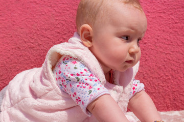 Little adorable blonde baby girl stands on her hands and this cute baby looking somewhere