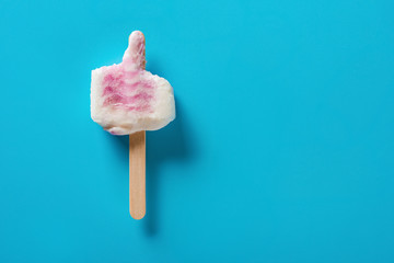mostly eaten pink color popsicle on a blue background