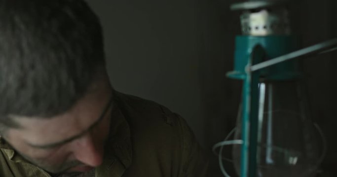 Close up on an unshaven ww2 soviet soldier man lighting a hurricane lamp striking the match before igniting the wick
