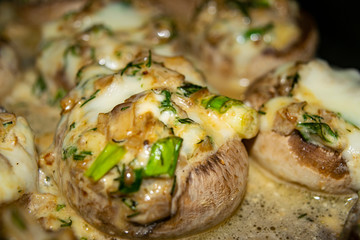 Mushrooms baked in the oven with cheese, green onions and dill. Close up.