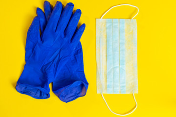 Latex gloves and medical face mask on a yellow background. Preventive protection against coronavirus.