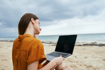 woman with laptop on the beach