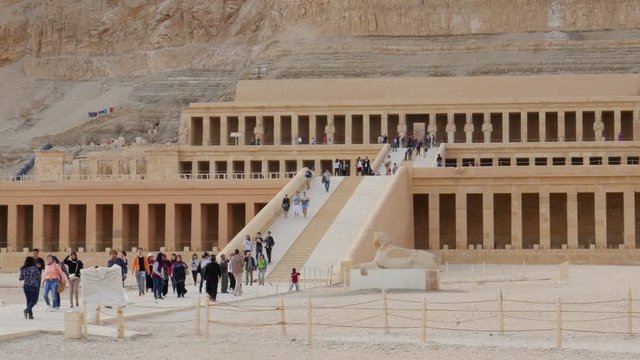 Lots of Tourists Came on an Excursion to the Archaeological Zone in the Vicinity of Luxor. They Can See Architecture of Ancient Egypt. The Temple of Hatshepsut Was Made in a High Cliffs.