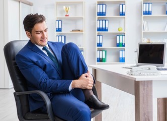 Young businessman doing sports stretching at workplace
