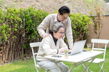 Using a laptop to wear an Asian elderly couple