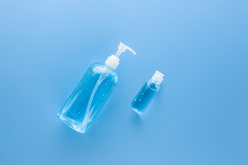 Alcohol hand gel sanitizer in big pump bottle and small travel bottle to protect from Coronavirus on light blue medical background