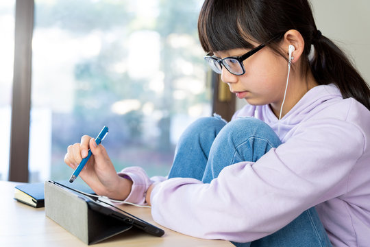 Female Asian Teenager Using Digital Tablet Indoors At Home