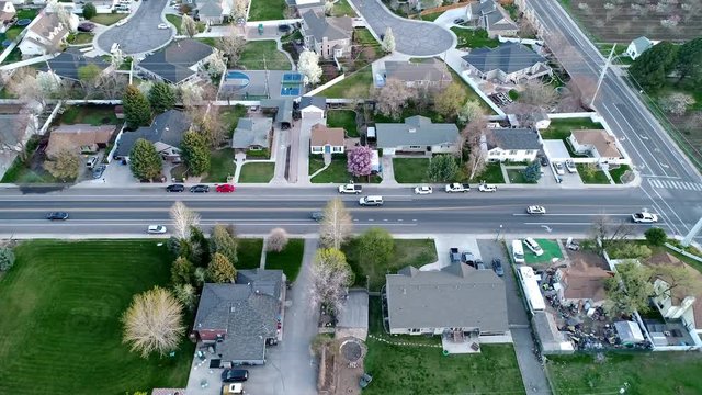 Flying parallel with traffic driving in neighborhood from aerial view.