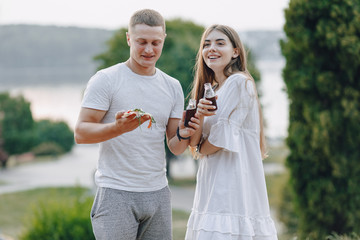 couple eating pizza and drinking in nature