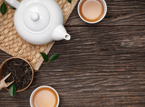 Cup of hot tea with teapot, green tea leaves and dried herbs top view on the wooden table empty space, Organic product from the nature for healthy with traditional style
