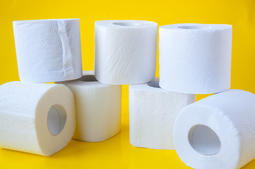 A pile of rolls of white toilet paper on a yellow background