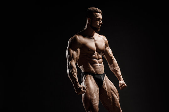 Muscular athletic bodybuilder fitness model posing. Isolated on black. Sport photo with dramatic light