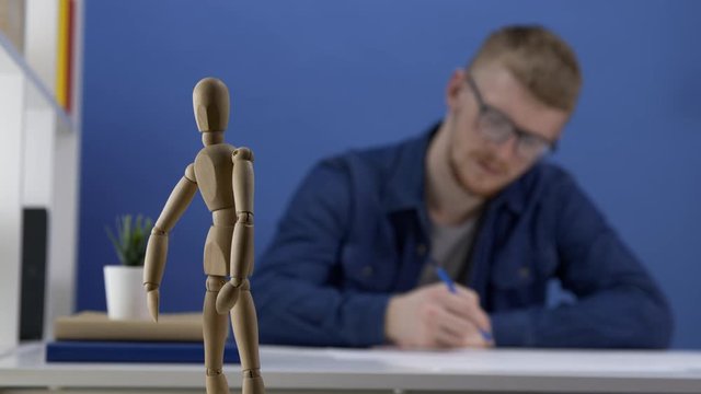 Young architect in glasses designs a wooden gestalt figure. The work of the artist or designer. The creative process. Creative workspace in blue tones. . Blur. Close up. Studio shot.
