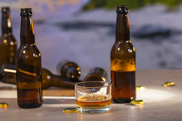 Short glass of beer with bottles and caps