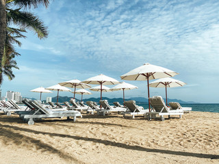 White soft sun loungers on the shore of a sandy sea beach. Tropical resort