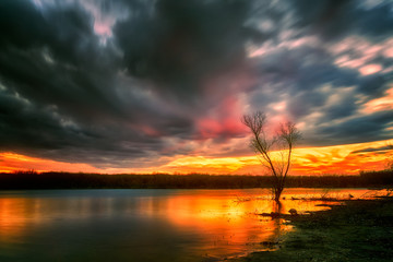 Beautiful sunset clouds over the lake with silhouette trees and long exposure silky smooth water