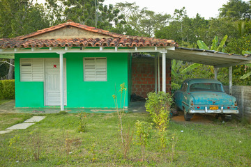 Green house and old car in carport in the Valle de Vi–ales, in central Cuba