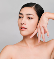 Beautiful young brunette posing,Youthful bright skin pretty Asian woman with clean and bright skin, Cosmetic Beauty Concept,hands touch on the cheek, smiling face isolated on grey background