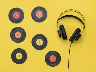 Vinyl discs and black headphones with a wire on a yellow background.