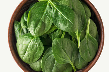 Spinach leaves in a clay Cup close-up on a light background. Food for fitness. The view from the top.