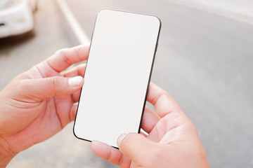 Mockup picture of business woman’s hands holding smart phone with white blank screen in modern place.