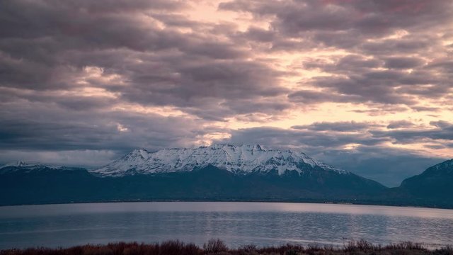 Time lapse of sunrise looking over lake towards snow capped mountains in Utah Valley.