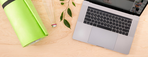 Online home training sports or yoga class concept top view Laptop with yoga mat on the wood floor