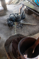 Old kettles on bonfire with manual coffee grinder