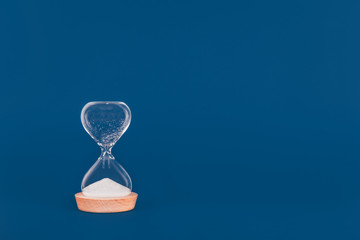 Hourglass with the finished sand. Concept of time and timely actions. Classic blue drop, with place for text