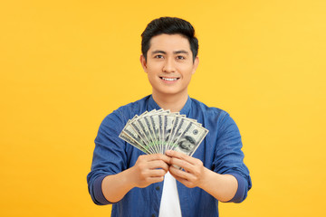 Astonished asian man holding bunches of dollars, lucky lottery winner