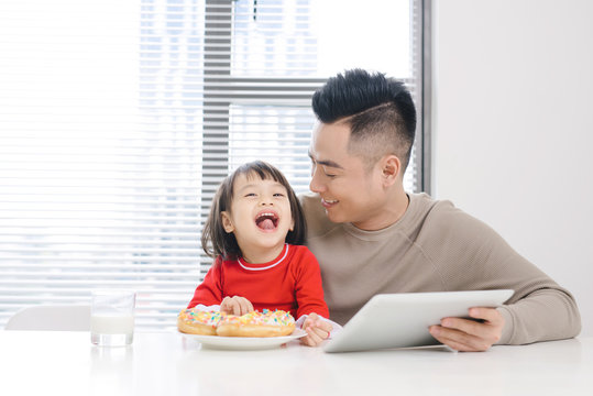 Young Dad And His Daughter Eating Pizza And Using Ipad.