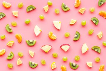 Colorful fruit pattern with citrus and kiwi slices - fresh summer fruits - on pink background top-down