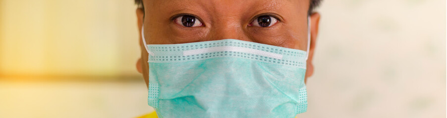 Asian man wearing protection face mask against coronavirus. Banner panorama medical staff preventive gear.