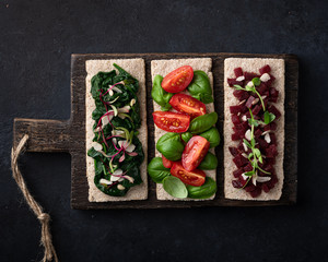 vegan sandwiches with spinach, nuts, tomatoes, basil, beets and micro greens on a dark background. View from above.