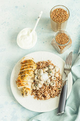 Grilled chicken breast, mushroom and tasty buckwheat porridge. Dietary balanced food. Light grey concrete background. Toned image.