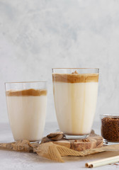 Glass with Dalgona frothy coffee. Trend korean drink with coffee foam on light grey stone background. 