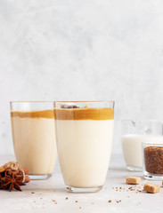 Iced Dalgona coffee in tall glass with spices. A trendy fluffy creamy whipped coffee. Korean coffee drink. Light grey concrete background. 