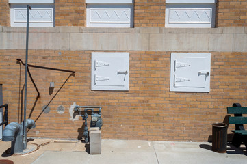 A gas meter and white metal utility doors in the side of a brick building