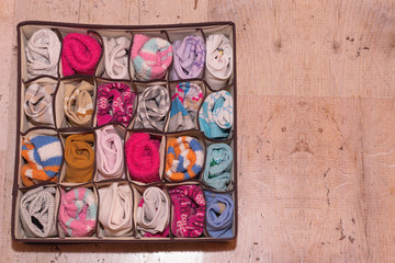 Various socks in a box organizer on a background of cork